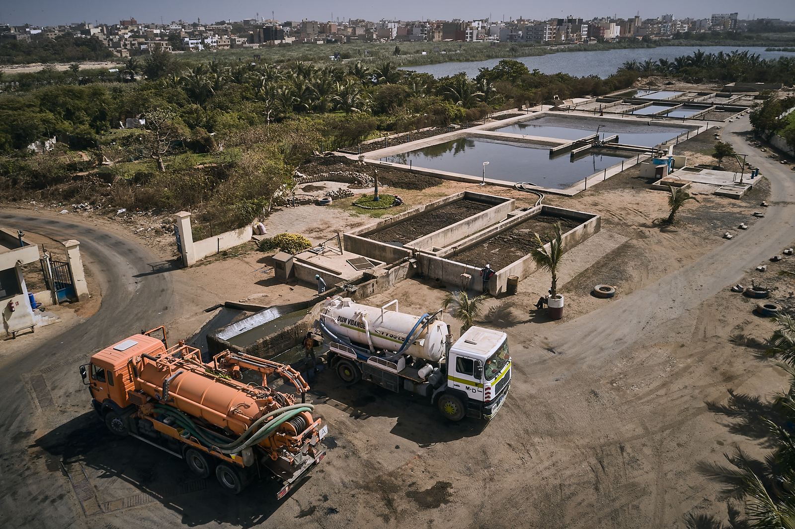 Vue aérienne par drone d'une station de traitement, avec ses bassins et deux camions hydrocureurs