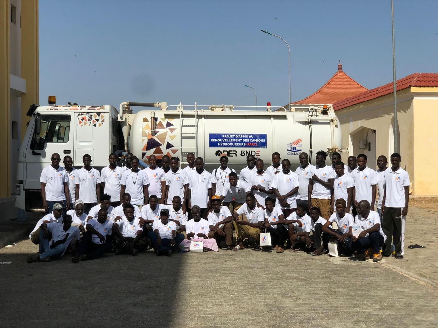 Groupe de participants à une formation, réunis devant un camion hydrocureur